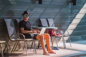guy on laptop with sunglasses and hat working as a digital nomad looking for remote jobs